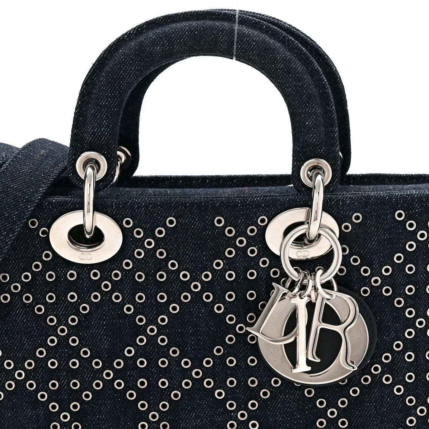 Denim handbag handle rings and silver-tone Dior charm over dark blue eyelet pattern