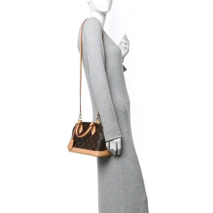 Small monogram tote bag worn on shoulder with tan leather strap and side profile