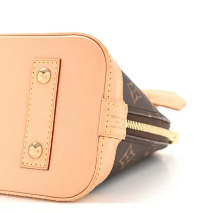 Monogram tote bag side close-up with tan leather panel, pocket, and zipper pull