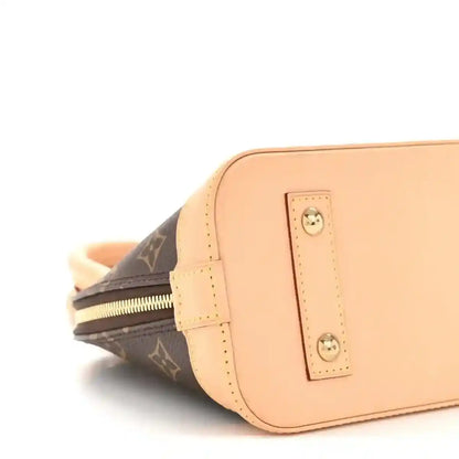 Monogram tote bag side close-up with tan leather front pocket and zipper track