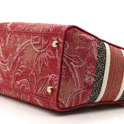Pink embroidered canvas handbag side panel with gold snaps and striped trim