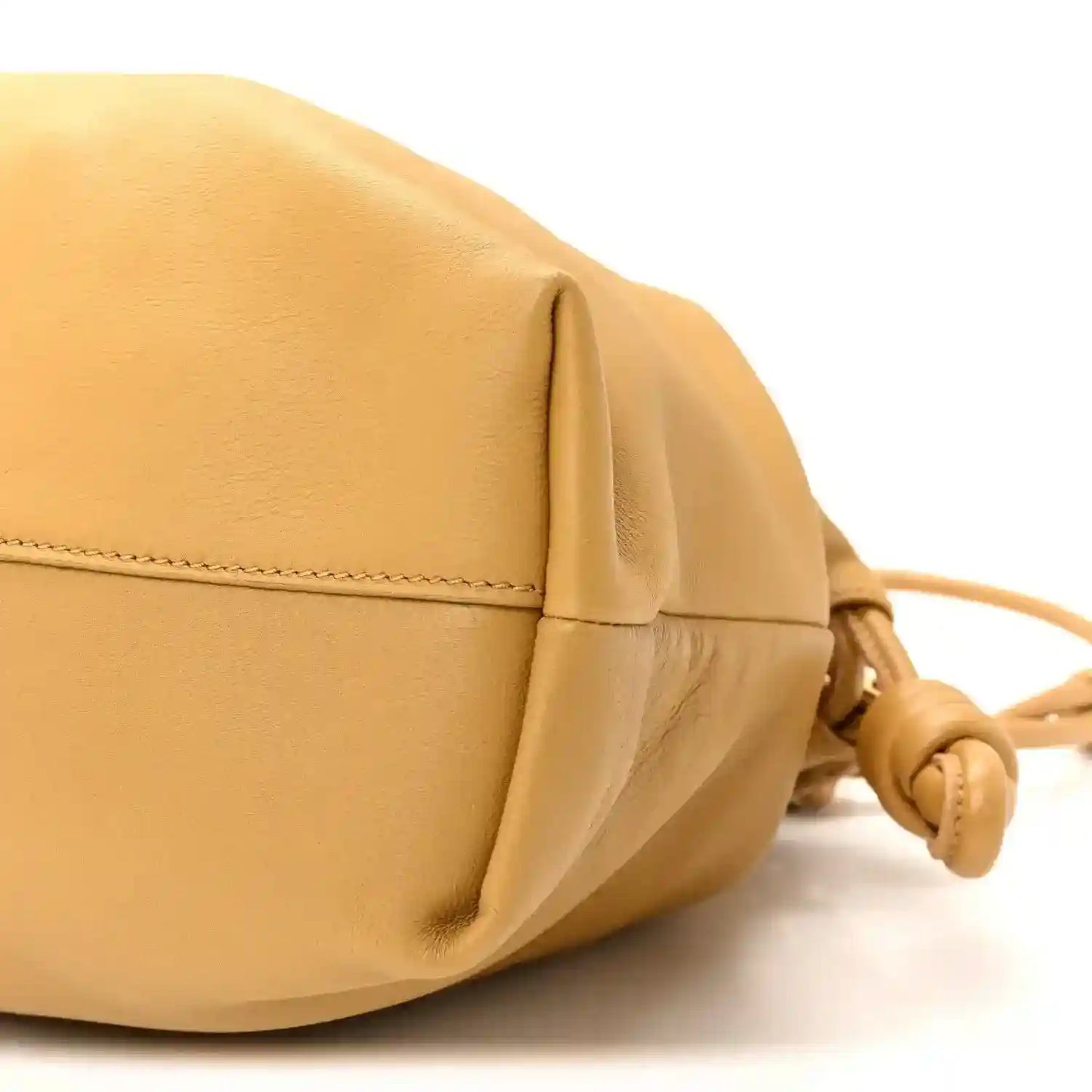 Tan leather clutch corner with stitched seam and drawstring cord hardware