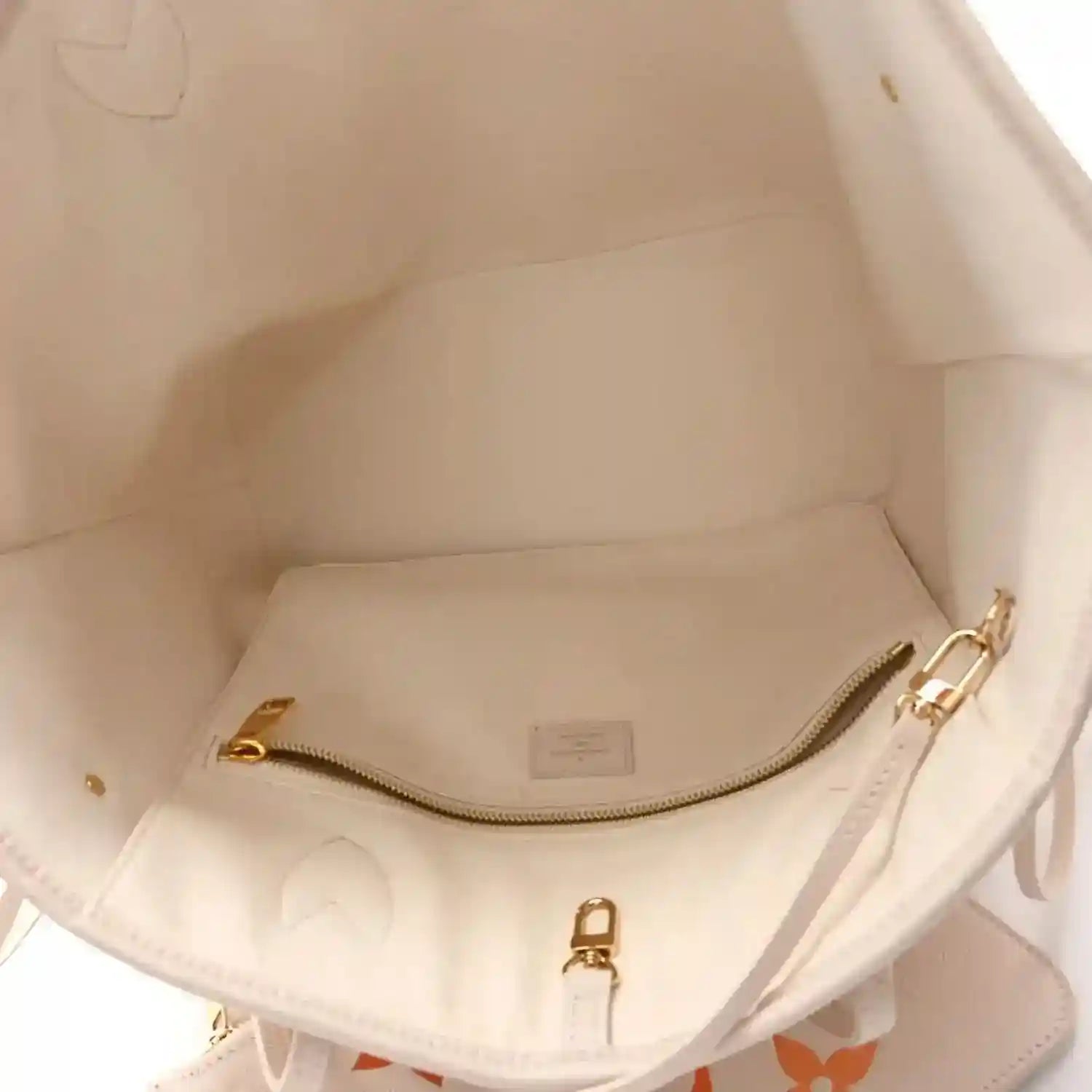Inside view of neutral tote with gold-tone zipper hardware and stitched seams