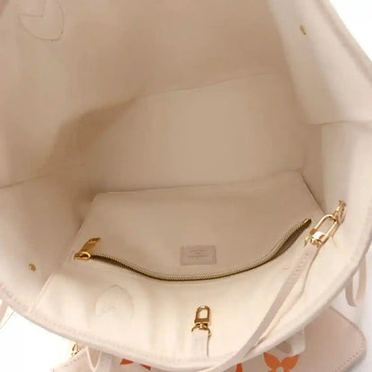 Inside view of neutral tote with gold-tone zipper hardware and stitched seams