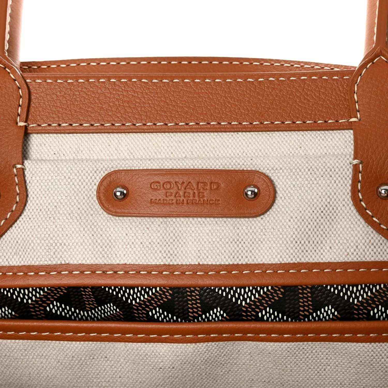Goyard Saigon tote handbag close-up of branded leather plaque and stitched top