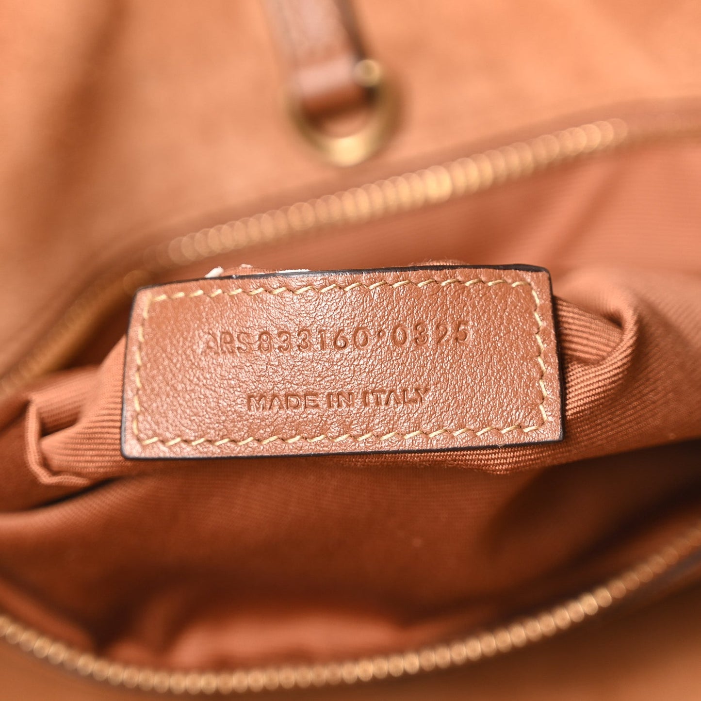 Close-up of tan-brown leather tote inner label reading "MADE IN ITALY"