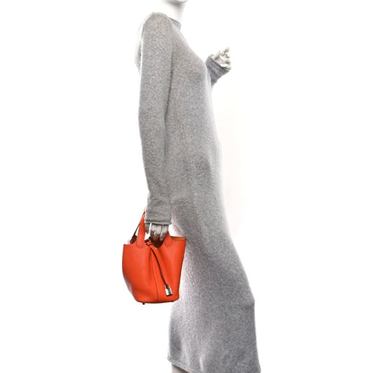Orange pebbled leather handbag worn crossbody with short strap and metal lock