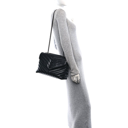 Quilted black chain satchel worn on shoulder, with small front flap and strap