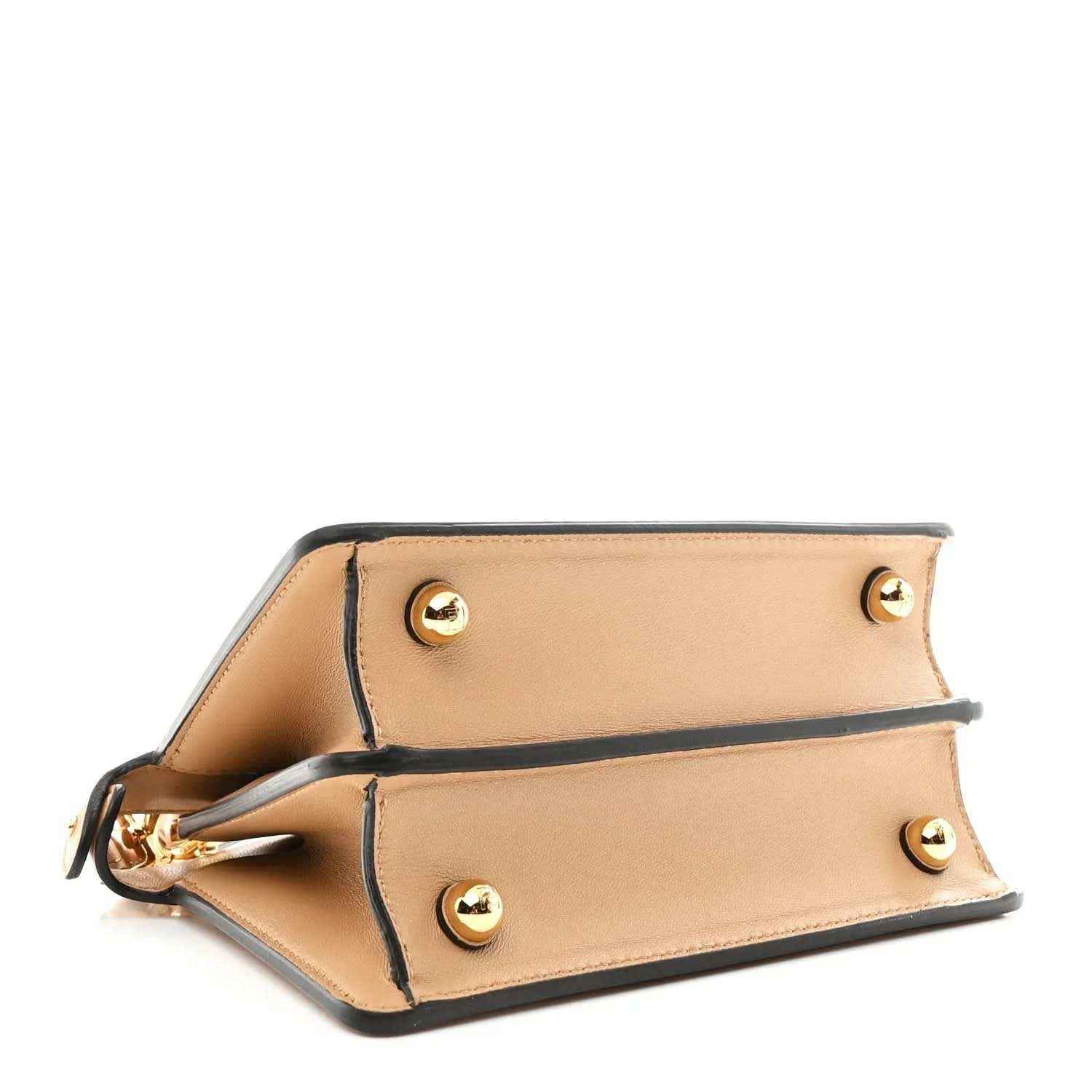 Tan satchel close-up with open flap, gold-tone rivets, and side frame stitching