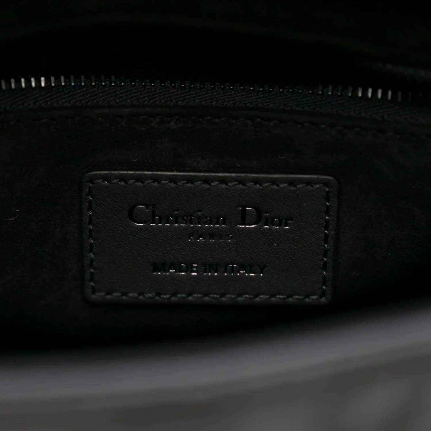 Interior label on a black Lady Dior handbag with zipper track visible