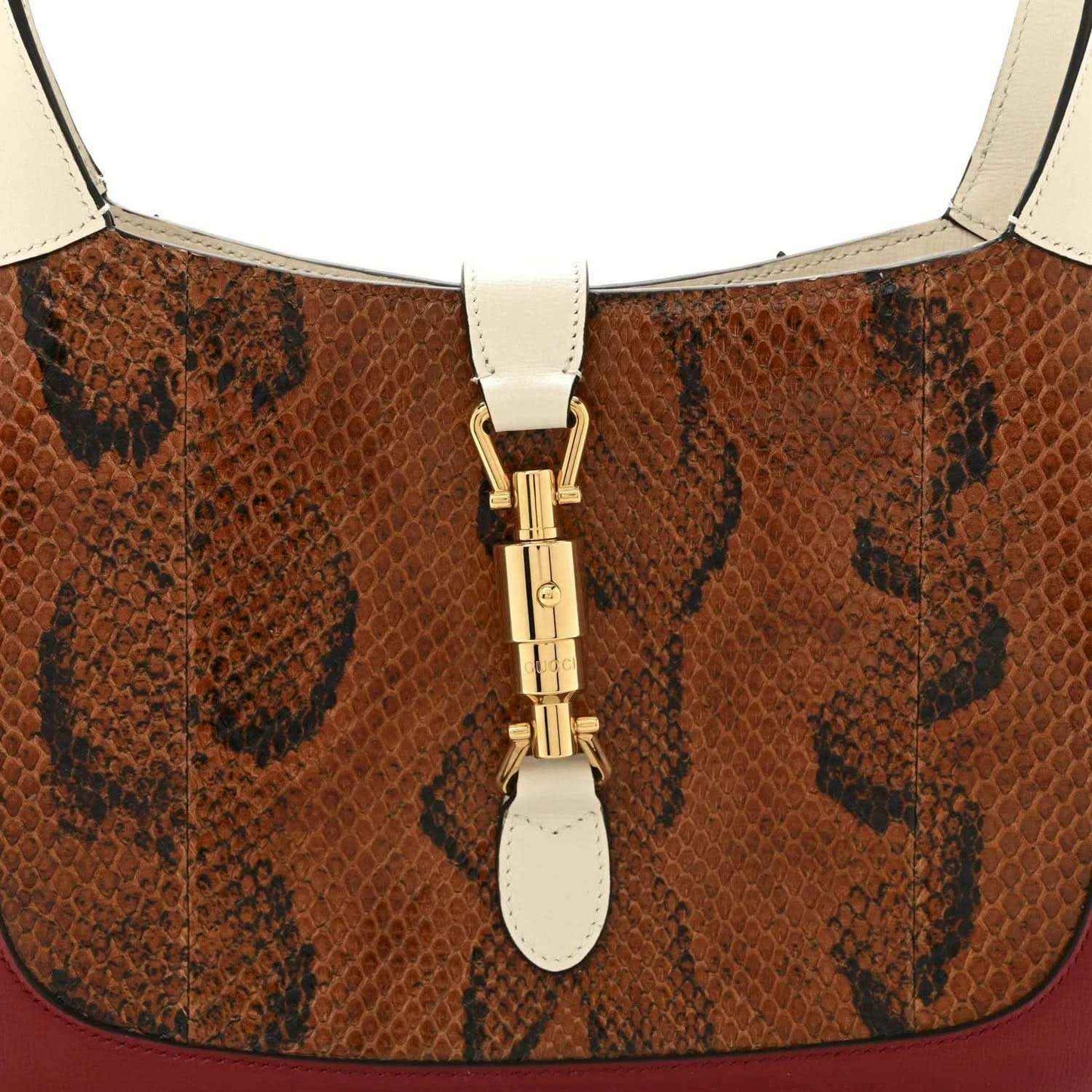 Snakeskin hobo bag top clasp with gold hardware and cream strap attachments.