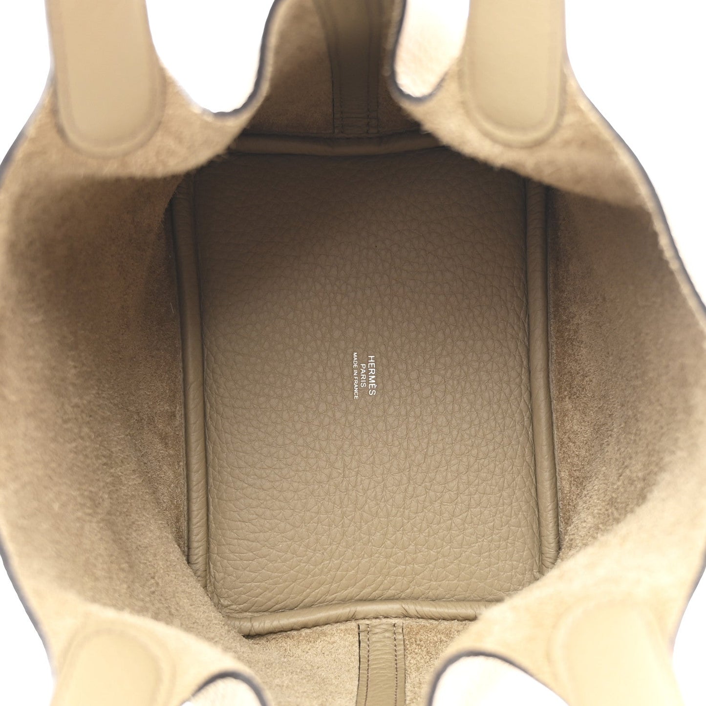 Beige leather handbag interior with fabric lining and small branding stamp