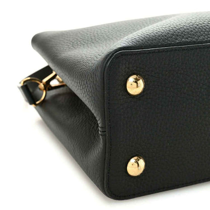 Black leather handbag corner with gold stud details and textured finish