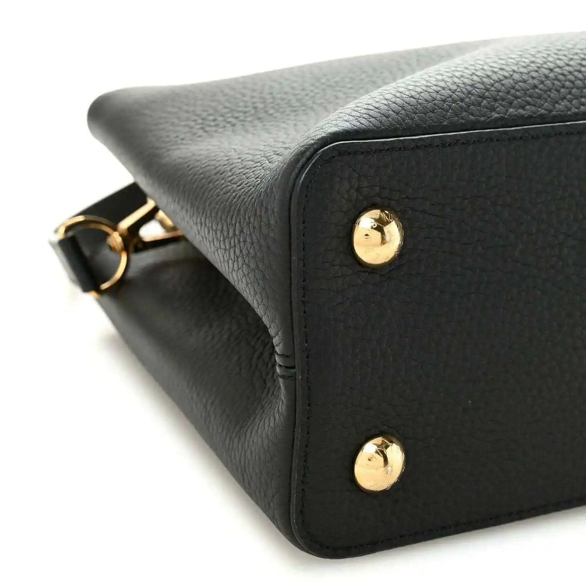 Black leather handbag corner with gold stud details and textured finish