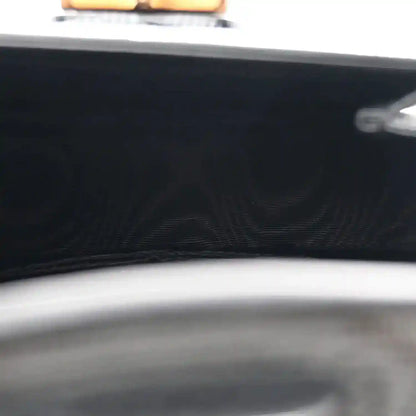Close-up of black bag front with embossed pattern and curved top edge trim
