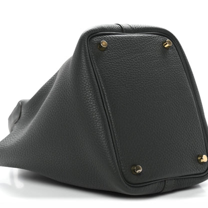 Side view of dark green textured mini bag with gold corner studs and curved base.