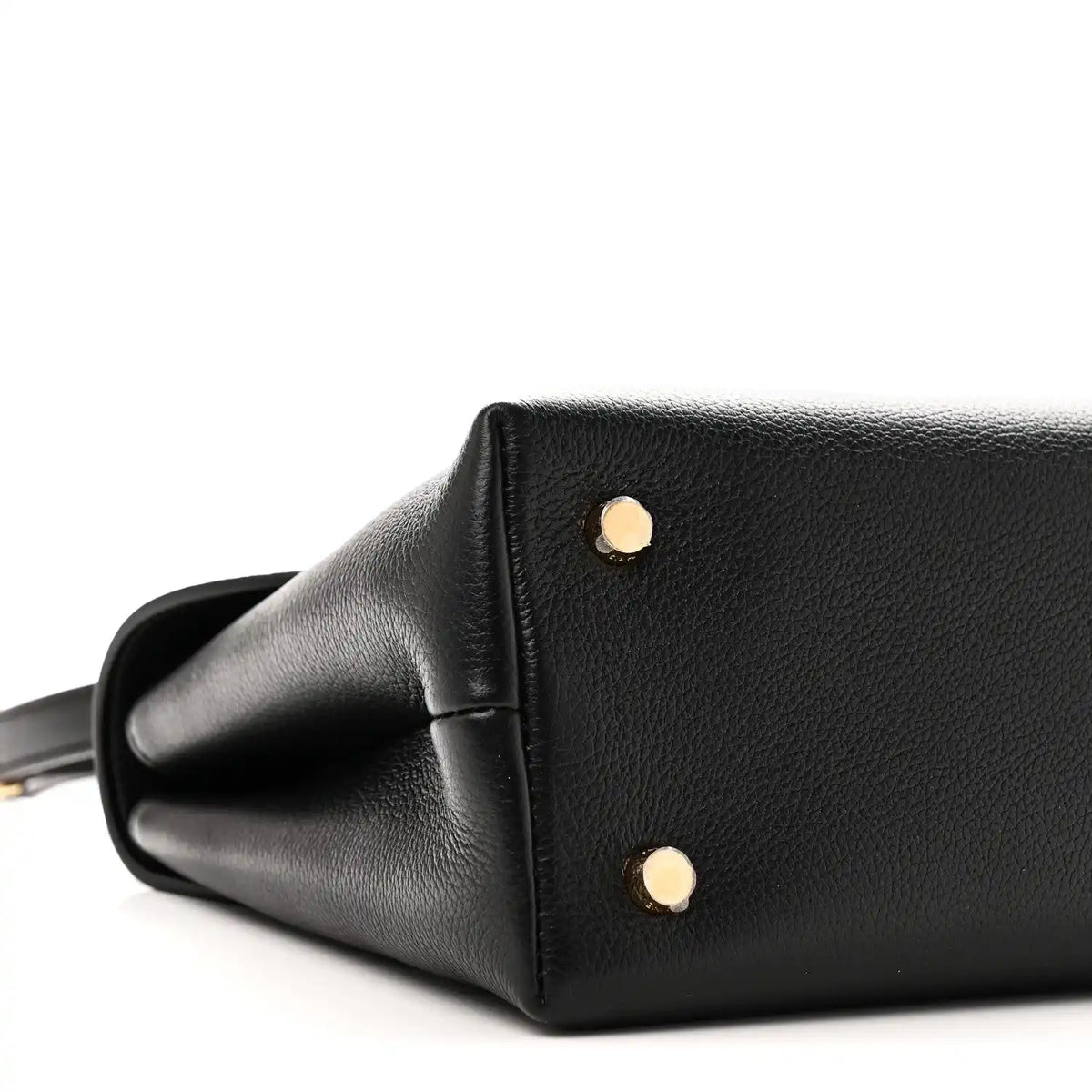 Black leather handbag side with two gold studs and curved corner seam