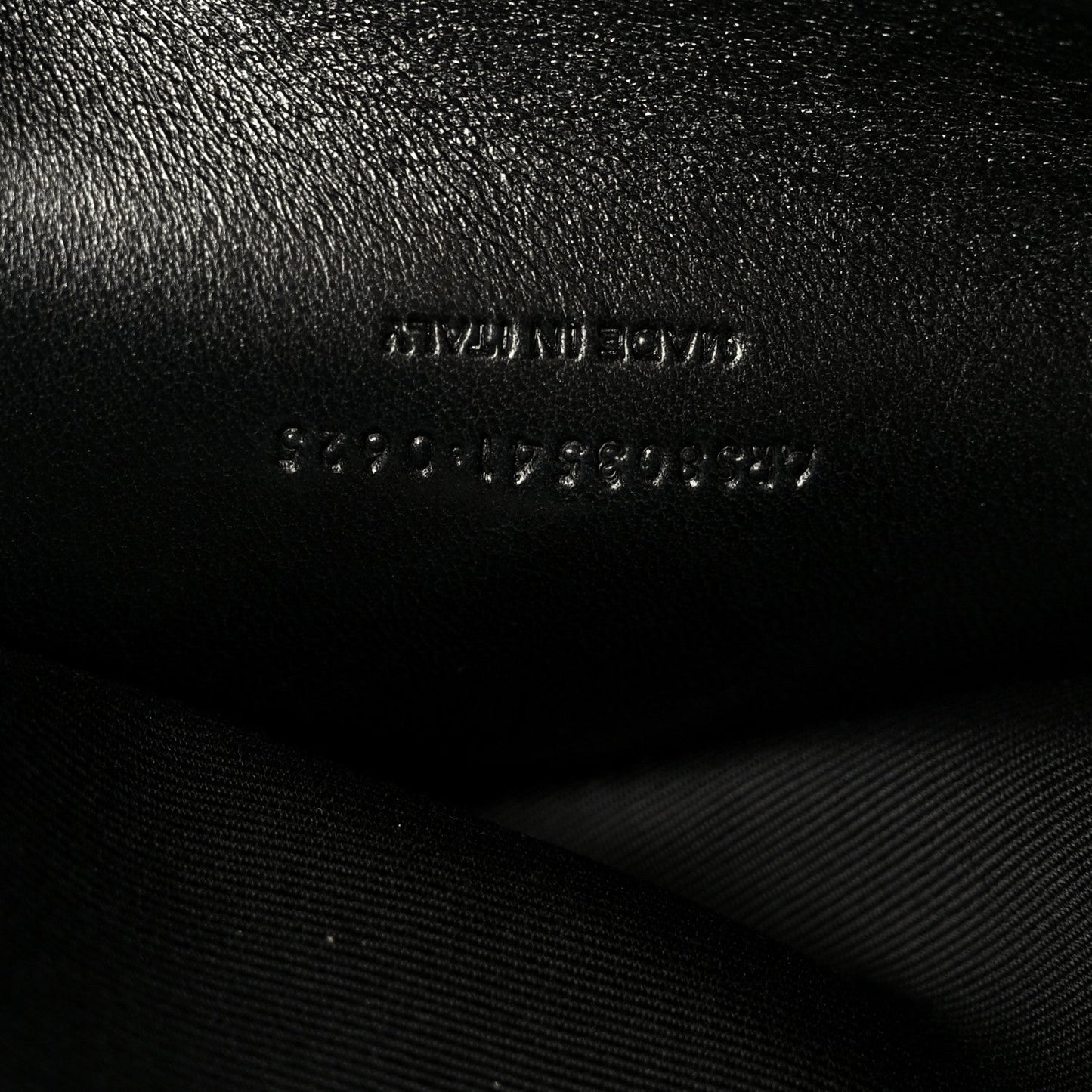 Black leather shoulder bag with embossed text and visible stitching