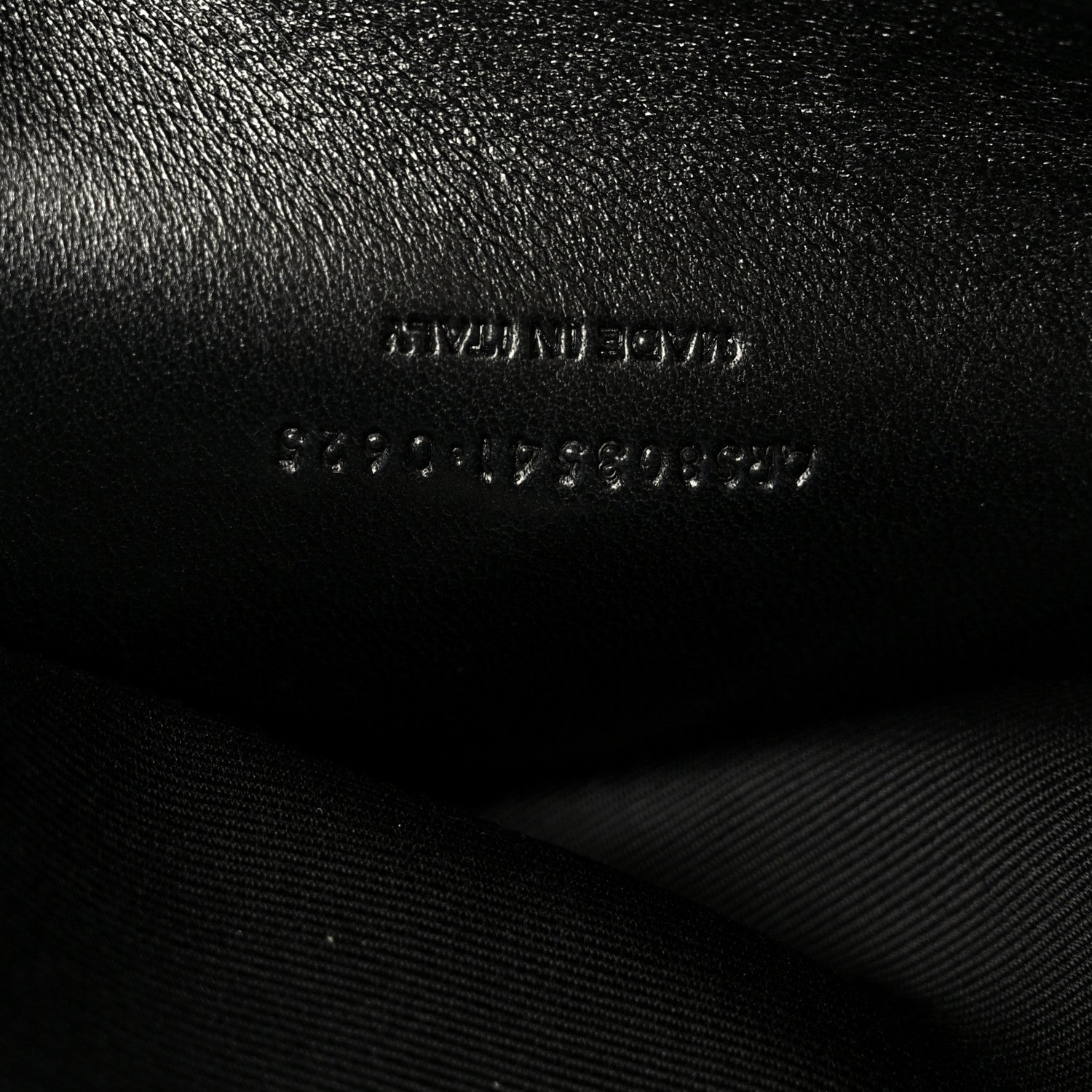 Black leather shoulder bag with embossed text and visible stitching