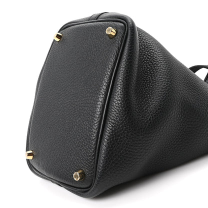 Black leather tote bag corner view with gold-tone studs and top handle loop