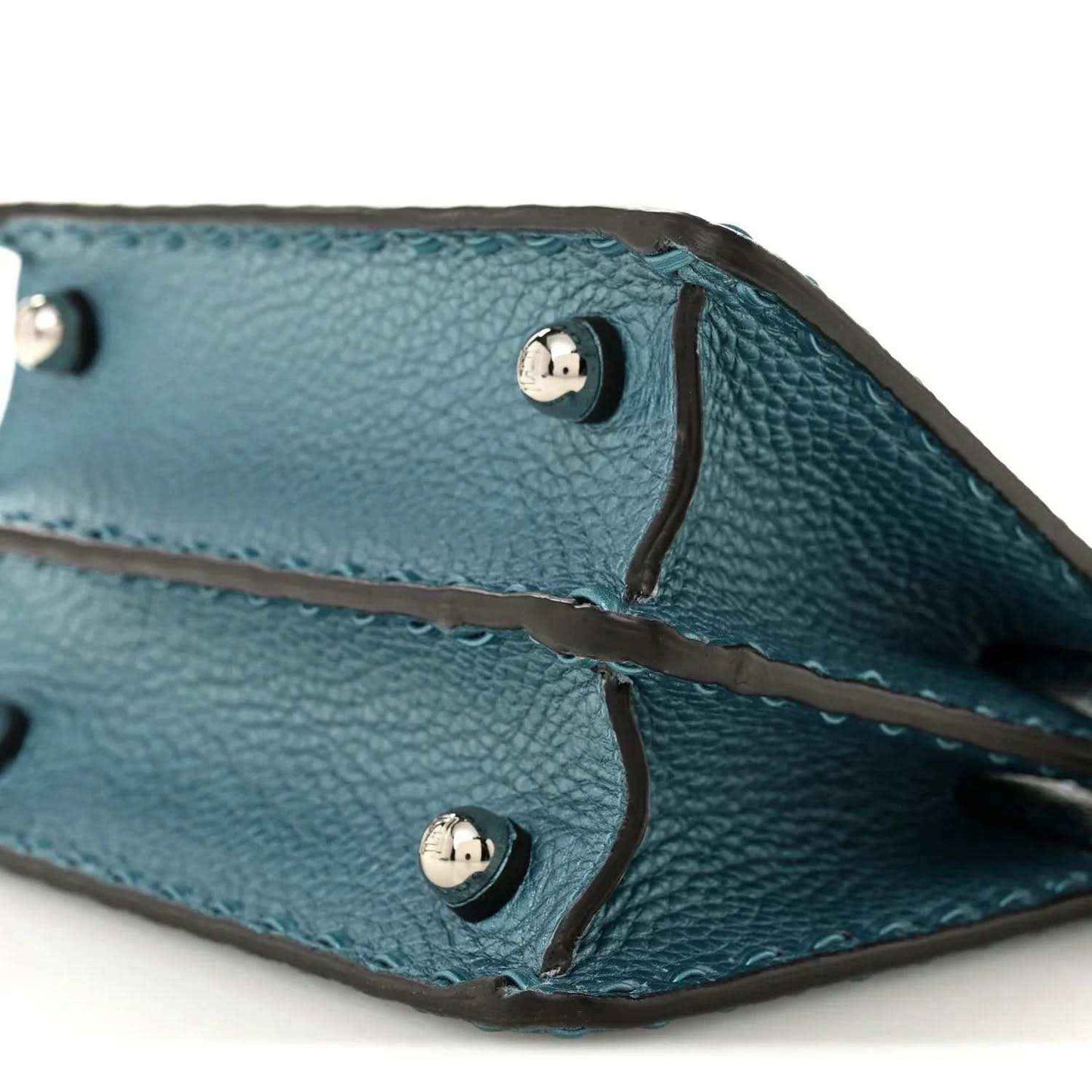 Blue leather satchel interior showing snap buttons and stitched leather tie straps.