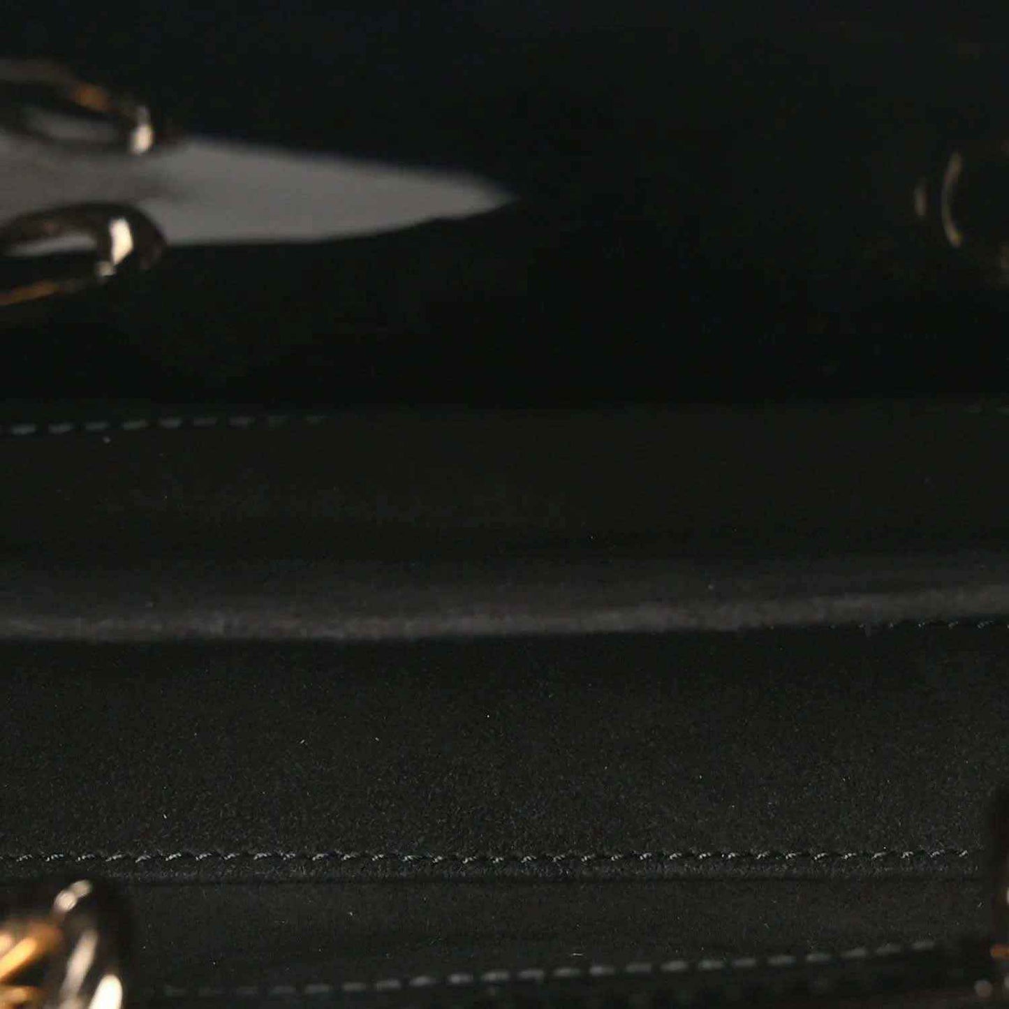 Close-up of black patent leather bag with stitched trim and textured surface