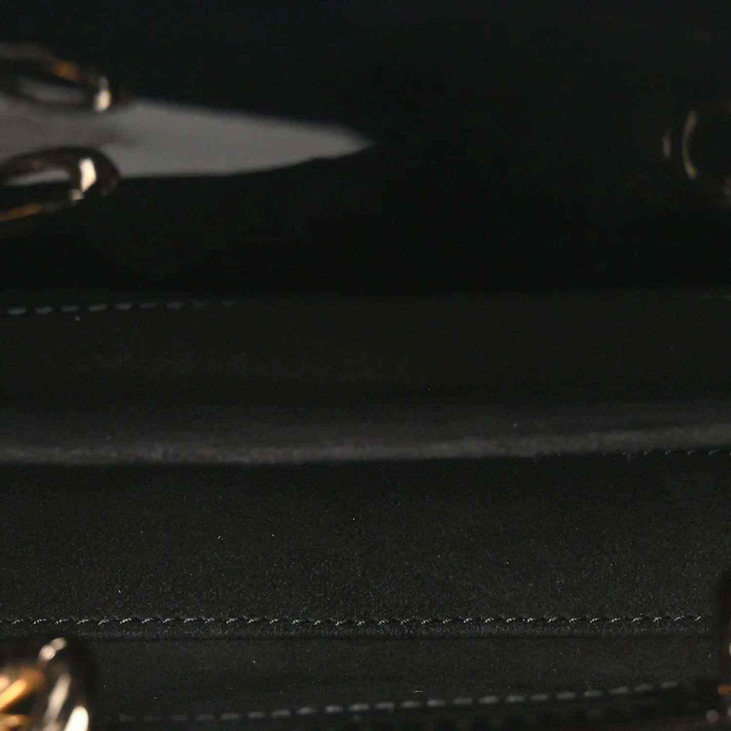 Close-up of black patent leather bag with stitched trim and textured surface