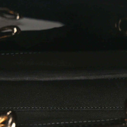 Close-up of black patent leather bag with stitched trim and textured surface