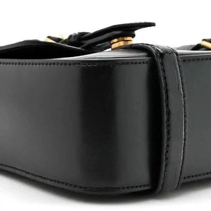 Black leather messenger bag close-up of top edge and strap attachment hardware
