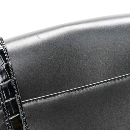 Black messenger bag corner with crocodile-embossed trim and double buckle detail