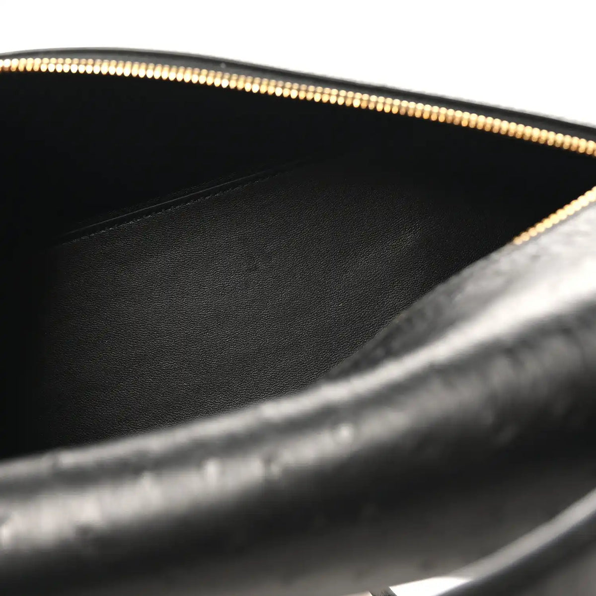 Black leather interior of ostrich bag with gold zipper trim and stitched lining.