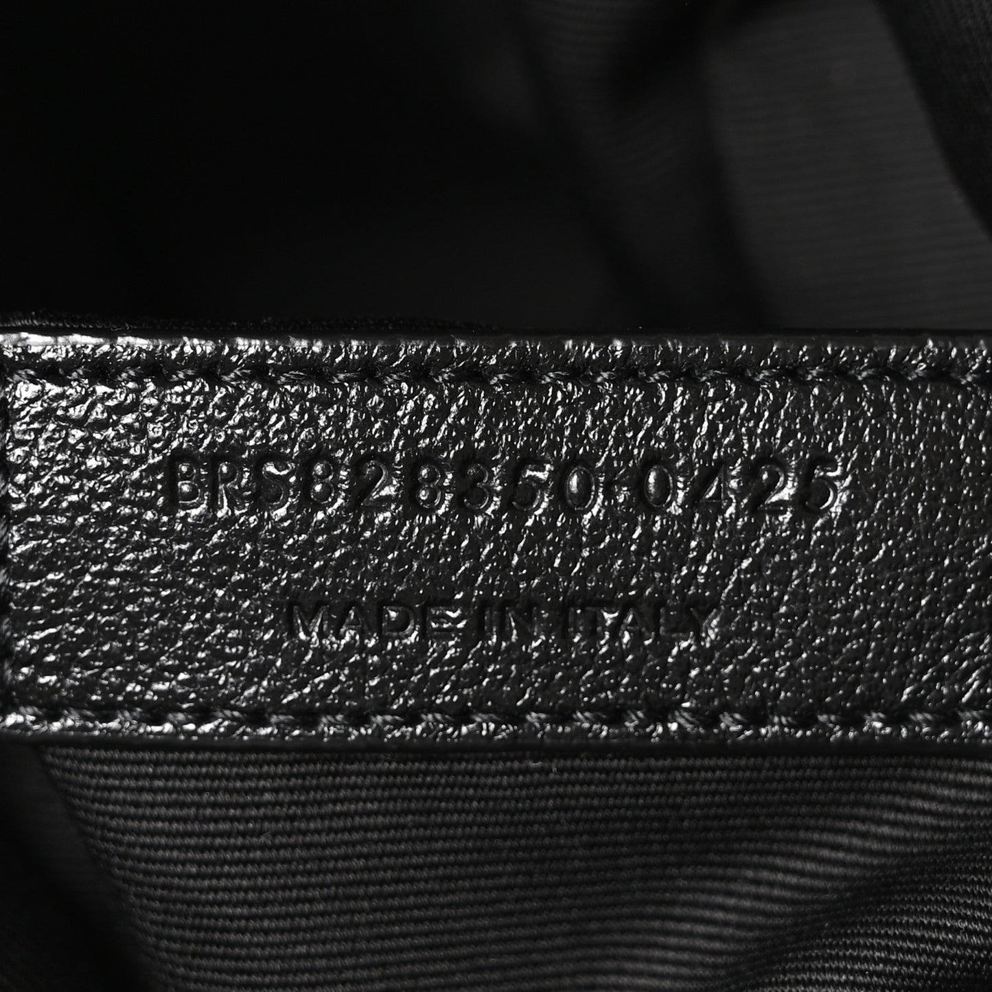 Embossed product code on black leather interior with stitched seam