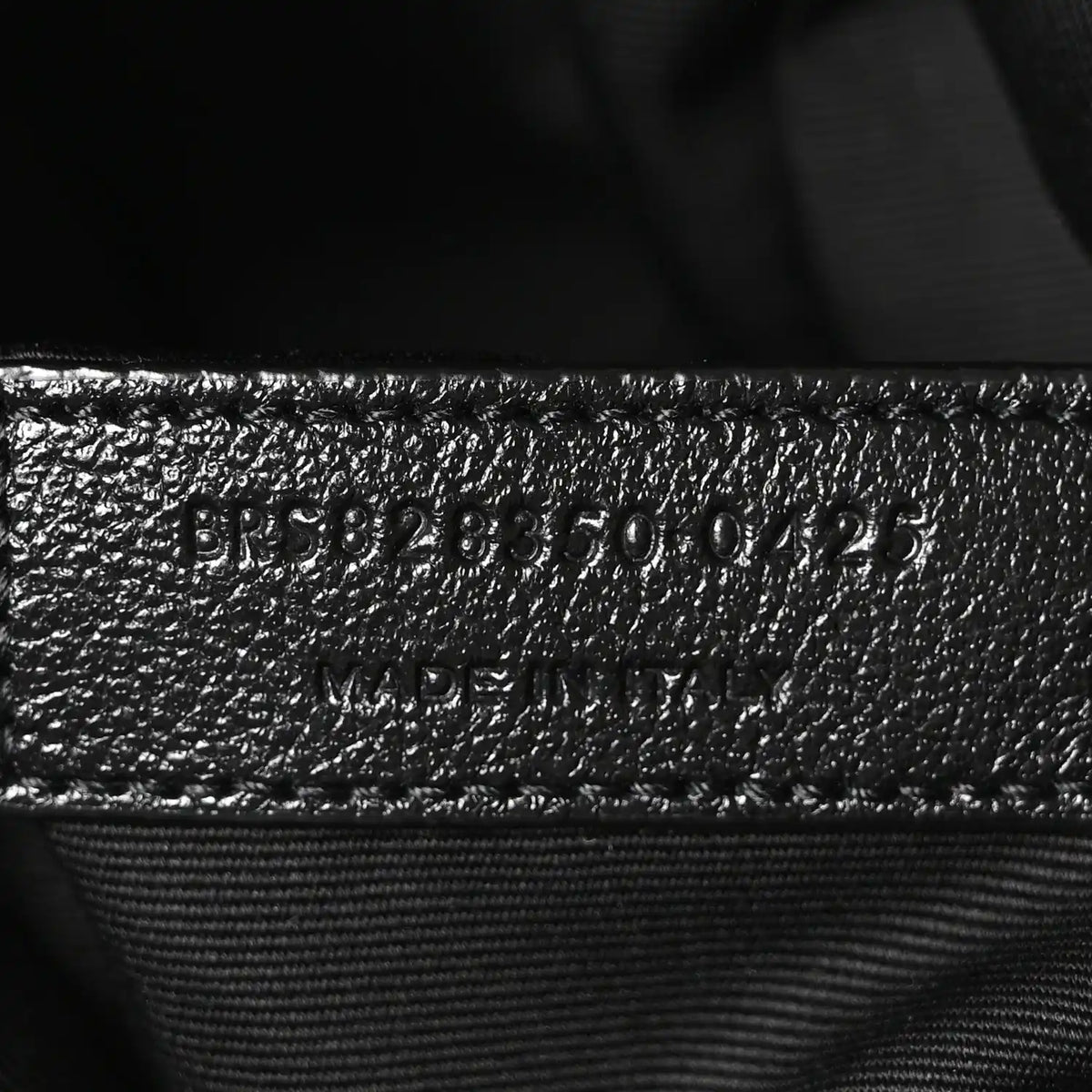 Embossed product code on black leather interior with stitched seam