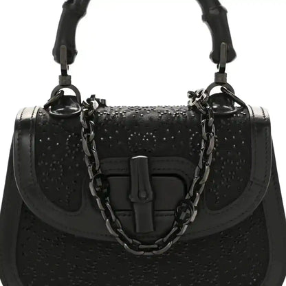 Black mini handbag with bamboo-style handle, chain strap, and front clasp detail.