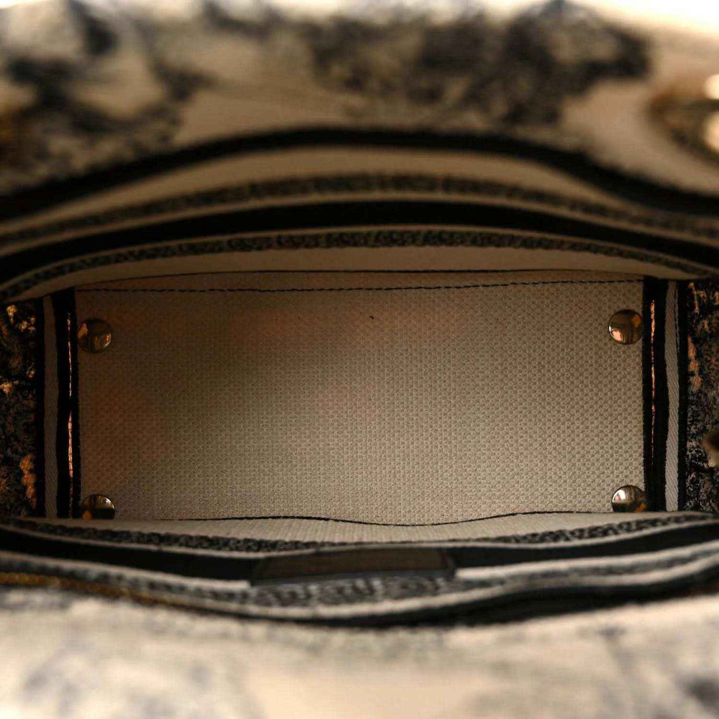 Tote handbag interior with metal rivets and fabric lining, open top view.