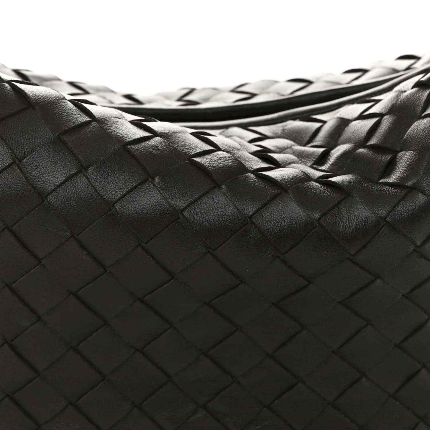 Close-up of woven leather intrecciato pattern on dark hobo bag