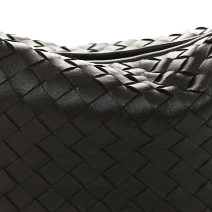 Close-up of woven leather intrecciato pattern on dark hobo bag