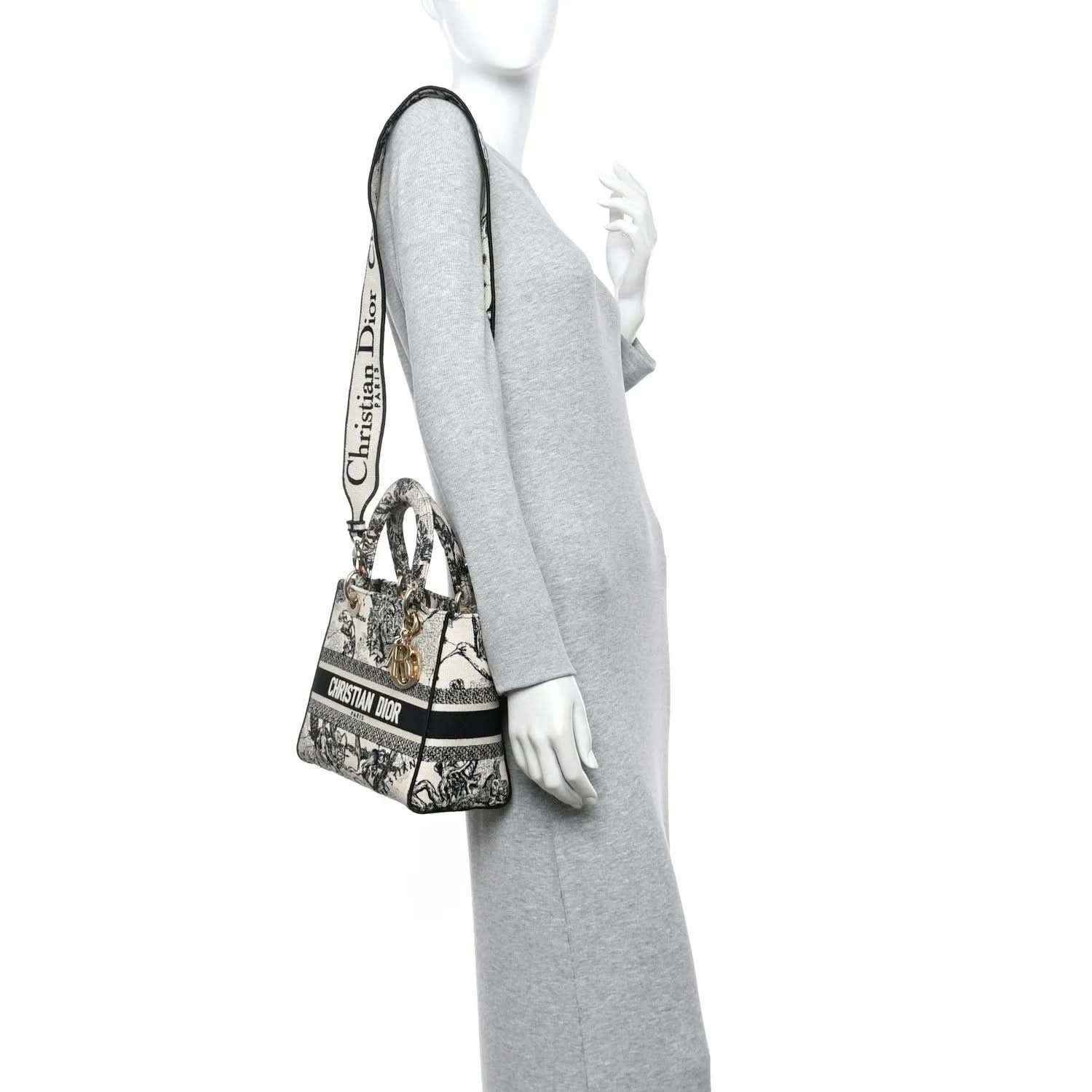 Medium tote handbag with toile print and adjustable shoulder strap, carried at side.
