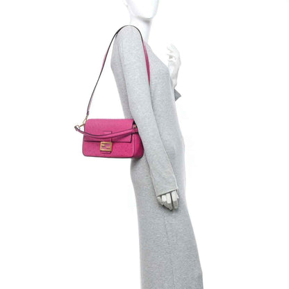 Pink baguette handbag worn crossbody with slim shoulder strap and gold-tone clasp