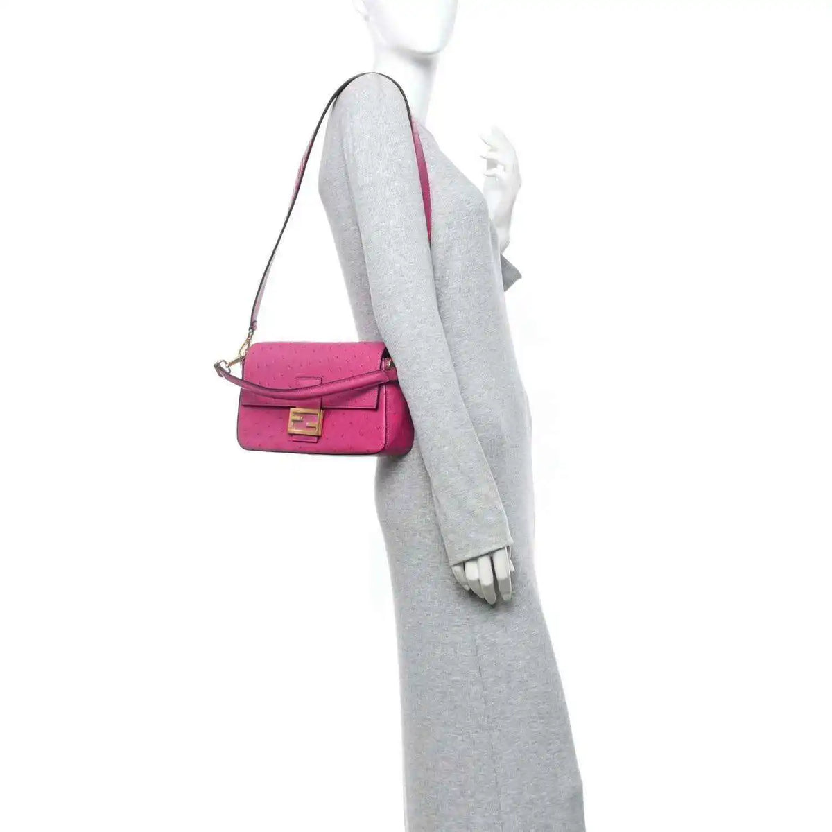 Pink baguette handbag worn crossbody with slim shoulder strap and gold-tone clasp