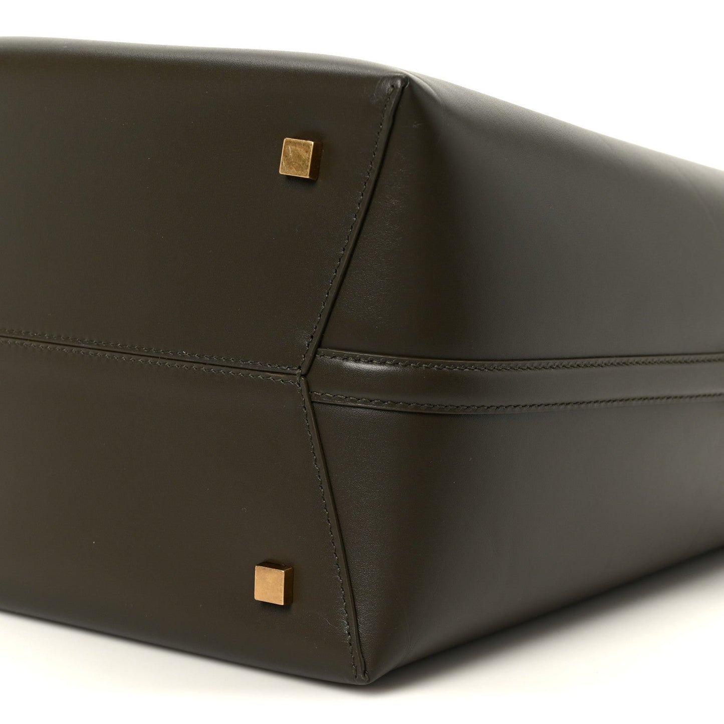 Shiny bucket bag corner with stitched seams and gold square studs.