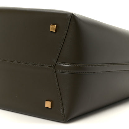 Shiny bucket bag corner with stitched seams and gold square studs.