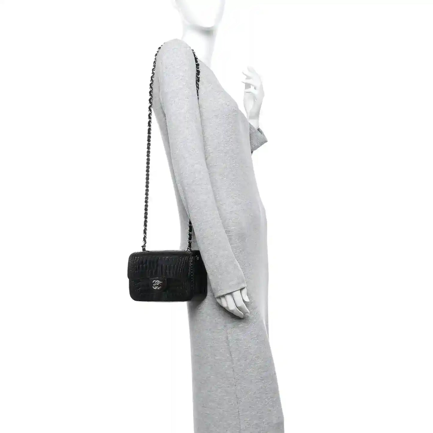 Black mini flap bag with short chain strap, worn crossbody on an arm.