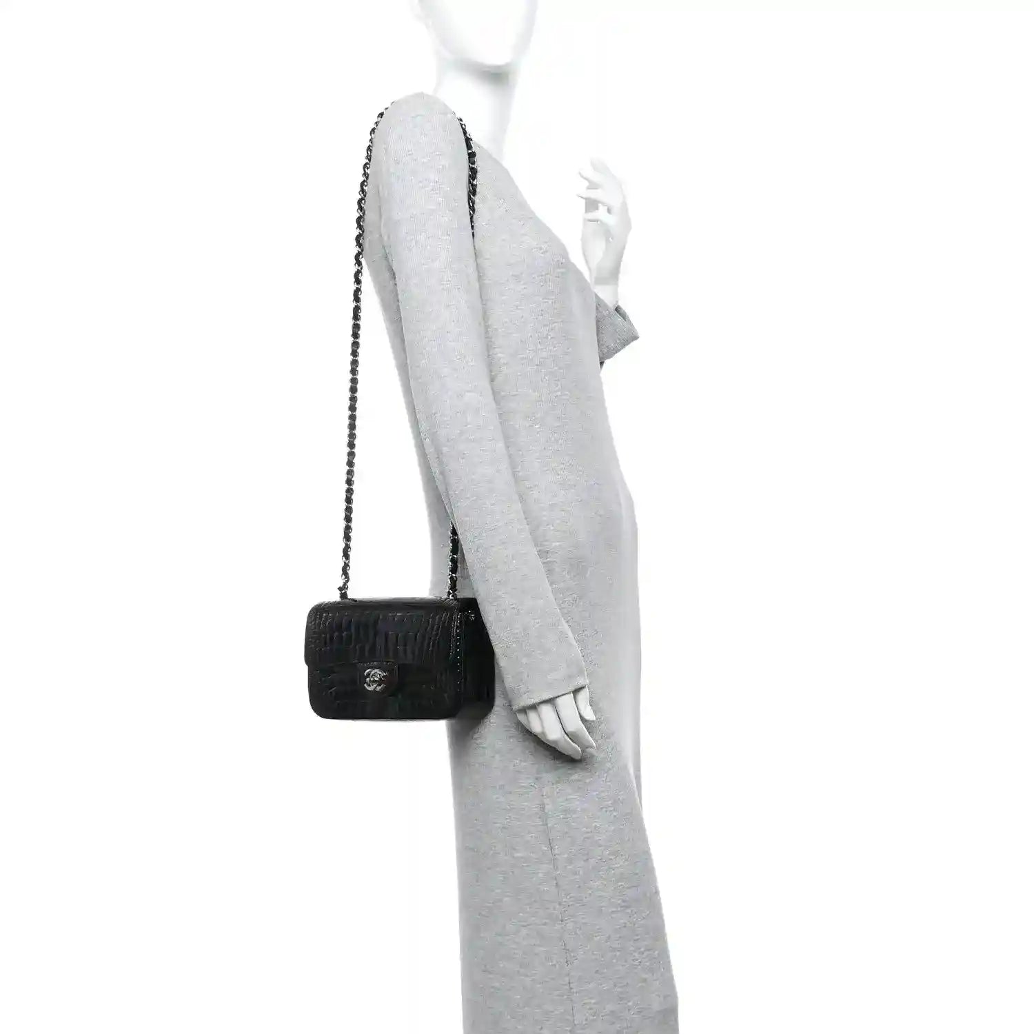 Black mini flap bag with short chain strap, worn crossbody on an arm.