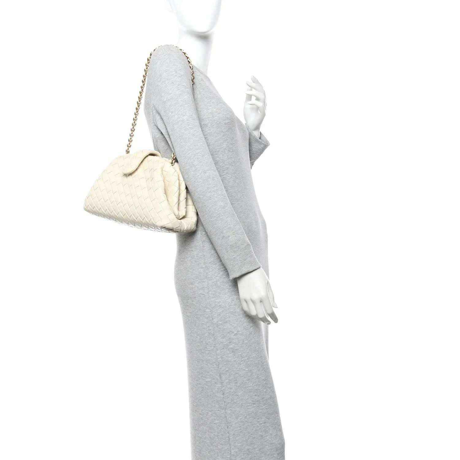 White leather mini clutch with gold-tone chain, held by a model