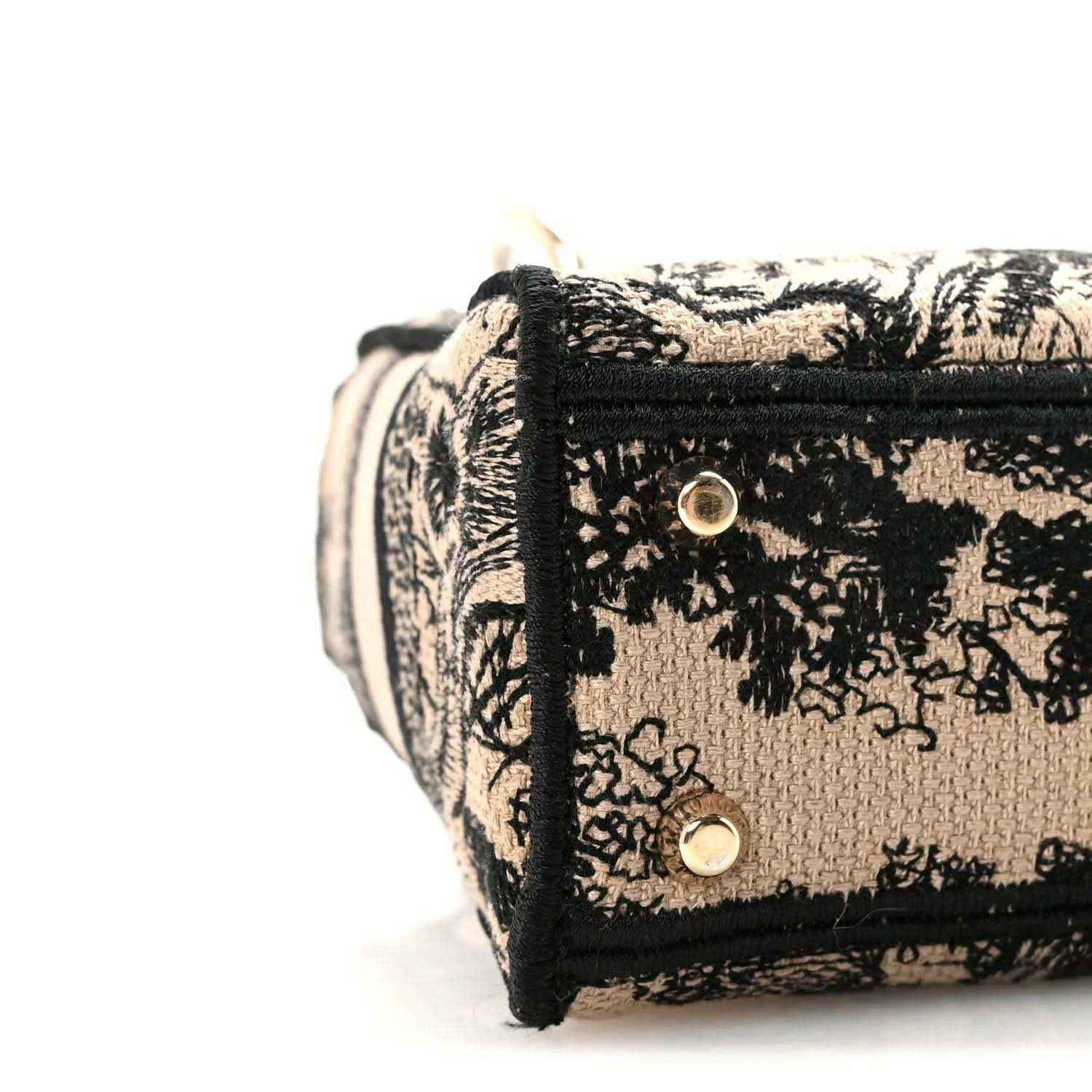 Side flap with two snaps on a black-and-cream embroidered mini handbag