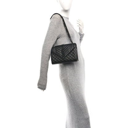 Saint Laurent black matelasse satchel on chain strap, worn at side on a model