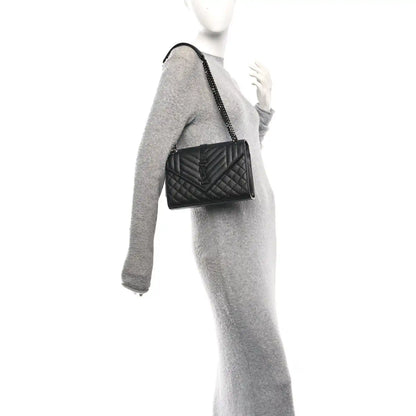 Saint Laurent black matelasse satchel on chain strap, worn at side on a model