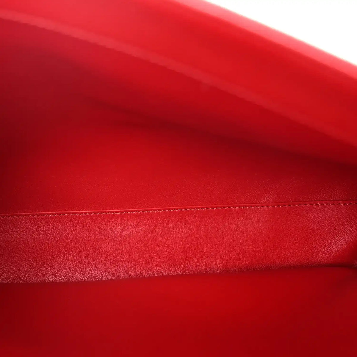 Close-up of red grained leather with contrast stitching along the bag edge
