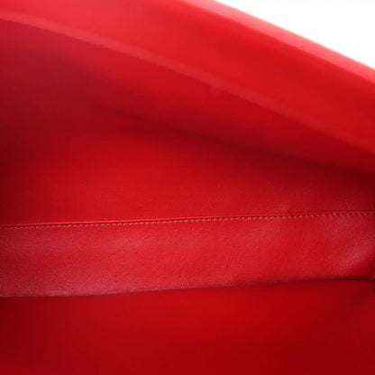 Close-up of red grained leather with contrast stitching along the bag edge